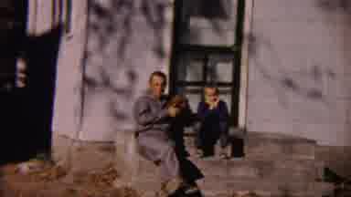 Cheyenne County Kansas (1959): Dad Dog And Child Sit On Front Steps On A Sunny Day