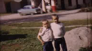 Cheyenne County Kansas (1959): Two Kids Posing For A Photo While A Woman Walks By