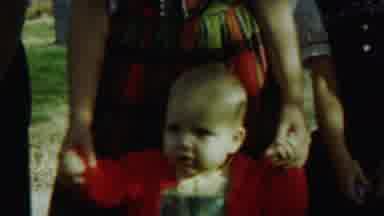 Saint Francis Kansas (1959): Light Skin Baby In Red Standing Supported By Young