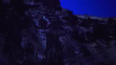 YELLOWSTONE WYOMING-1967: Pan Of Rocky Hillside At Nighttime Against Blue Sky