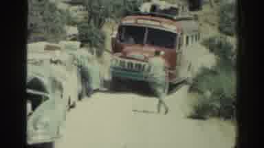 RHODES GREECE-1962: Man Directing Red Bus Through Dusty Road Traffic
