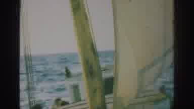RHODES GREECE-1962: Old Sailboat Rocking On Sea With Three Men Standing On Deck