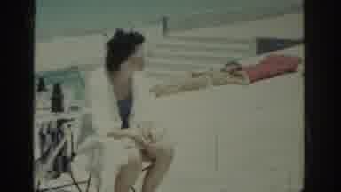 RHODES GREECE-1962: Woman Wearing Blue Swimwear Sits In Green Poolside Chair On