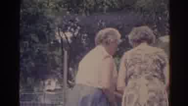 Florida USA (1962): Two Elderly Ladies Wearing Aprons Help Each Other Outside