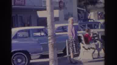 Florida USA (1962): Two Women Sitting At A Bus Stop On A Sunny Day With Cars In