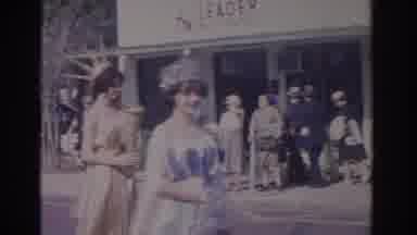 Florida USA (1962): Man Wearing Grey Suit Stands Next To Woman Dressed In Red