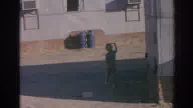 Izmir Turkey (1962): Child Wearing Tan Pants Holds Small Stringed Object Behind