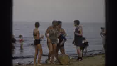 New Jersey USA (1963): Woman Wearing Grey Swimwear Rolls Brown Object With Foot At