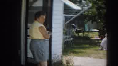 New Jersey USA (1963): Woman Wearing Grey Shorts Walks Towards Blue Car On A Sunny