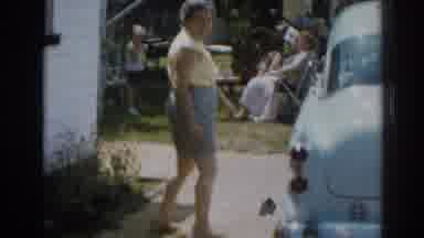 New Jersey USA (1963): Woman Wearing Grey Shorts Walks Alongside Of Blue Car On A