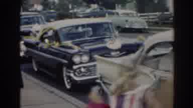 New Jersey USA (1963): Two Girls Run Past Parked Cars On A Clear Day