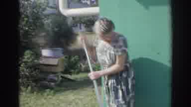 Norfolk Virginia (1966): Woman Wearing Grey Dress Dress Sweeps Outside On A Bright