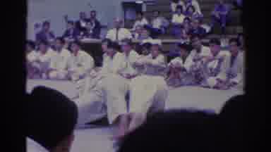 West Covina California (1966): Man Wearing Black Suit Watches Two Men Wrestle On