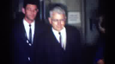 Los Angeles California (1967): Woman Wearing Blue Dress Stands Next To Men Wearing