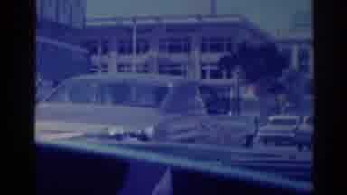 Los Angeles California (1967): View Of Man Wearing Black Suit Holding Square Brown