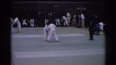Los Angeles California (1967): Man Wearing Black Suit Trots Past Karate Match In