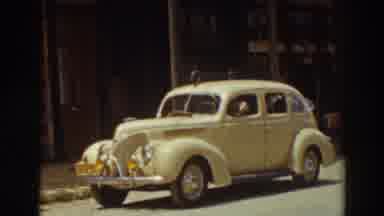 Truckee California (1937): Brown Dog Looks Out Window Of Parked Yellow Car On A