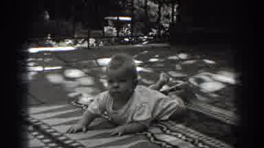 New Jersey (1938): Baby Wearing White Shirt Lies On Blanket Smiling At Camera
