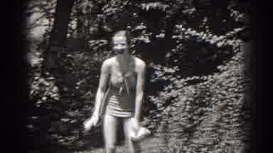 New Jersey (1938): Woman Wearing White Swimwear Stands In Front Of Brush On A