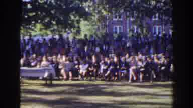 Florida (1941): People Sit On Chairs And Stand Outside On A Field In Front Of A