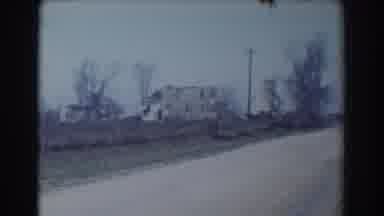 York Nebraska (1958): Grey Car Speeds Down Dirt Road On A Clear Day
