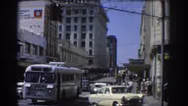 Brisbane Australia (1967): A Busy Street With Bus And Old Cars And People Walking