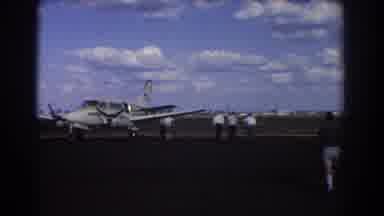 Brisbane Australia (1967): A Small Plane Parked On A Runway With Men Standing Near