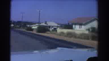 Perth Australia (1967): Car Passing Through A Road With Similar Houses And Bushes