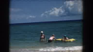 Florida (1957): Woman Wearing White Shorts Waves To Camera While Standing In Sea