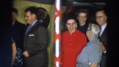 Wheeling Ohio (1957): Woman Wearing Red Dress Stands Next To White Pole Decorated