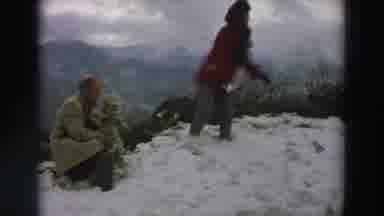 Italy (1958): Man Sitting With Baby And Woman Making Snowball In Mountainous Area