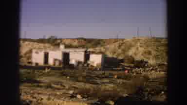 Italy (1958): Old Abandoned Buildings In A Desert With Barrels Out Front