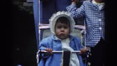 Bel Air Maryland (1960): Baby Wearing Blue Coat Sits In Silver Stroller Sucking