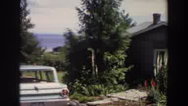 Washington (1964): View Of Blue Car Parked Next To Grey House On A Clear Day