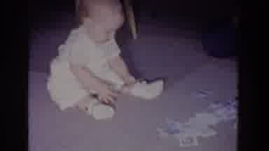 Fallston Maryland (1965): Baby Wearing White Romper Sits On Floor Holding Playing