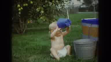 Fallston Maryland (1965): A Small Blonde Haired Baby In A Diaper Tries To Pour A