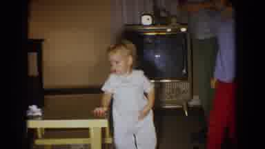 Fallston Maryland (1965): Baby Wearing Blue Overalls Stands Next To Yellow Table