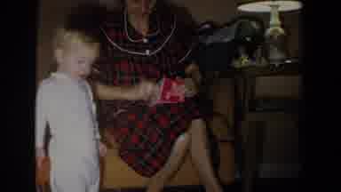 Fallston Maryland (1965): Woman Wearing Red Plaid Robe Opens Box For Child Wearing