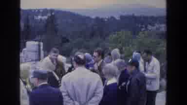 ATHENS GREECE-1976: A Group Of People Gathering At A Structure With Mountains In Background