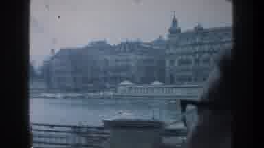 ZURICH SWITZERLAND-1976: Man Wearing Glasses Looks Out Window Of Train Towards River City