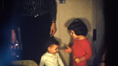 Aliquippa Pennsylvania-1958: Young Girl in Red Outfit Interacts with Toddler in Home Interior