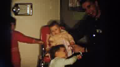 Aliquippa Pennsylvania (1958): Man Wearing Black Shirt Smiles At Baby Sitting In