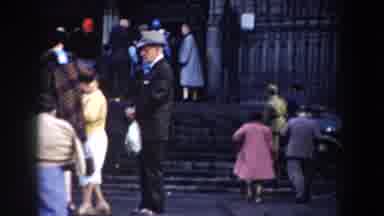 BARCELONA SPAIN-1959: People Entering Dark Grey Stone Building On A Windy Day