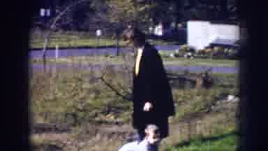 Nebraska (1956): Adult Standing Up Looking At Child Crawling On The Grass