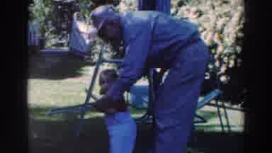 Tustin Wisconsin (1964): Man Wearing White Hat Helps Toddler Wearing White Pants