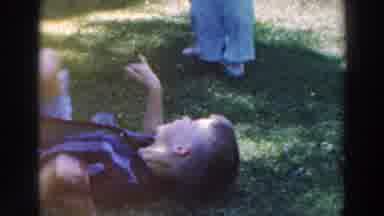 Tustin Wisconsin (1964): Woman Wearing White Sweater Helps Baby Wearing Red Shirt