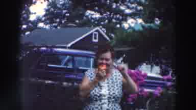 Tustin Wisconsin (1964): Woman In Floral Gown With Brown Hair Takes A Bite Of