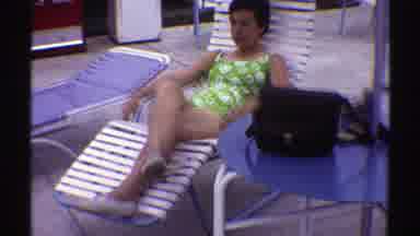 Nebraska (1969): Woman In Green Bikini Sitting On Beach Chair Relaxing