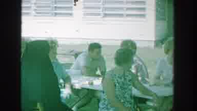 Michigan (1964): A Group Of People Are Seen Outside Of Some Buildings Seated At A