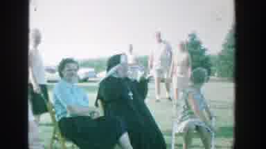 Michigan (1964): A Group Of People Sitting And Watching A Boy Playing Baseball On